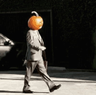 Man In Suit With Pumpkin Head Walking Down Street GIF
