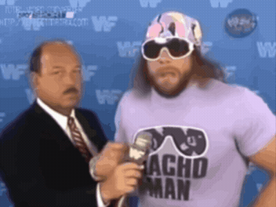 Man In Sunglasses And Acho Man Shirt Talks Into Microphone GIF