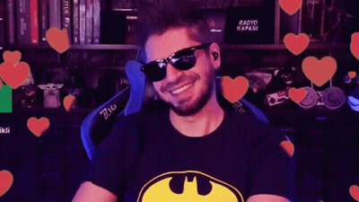 Man In Sunglasses And Batman Shirt Smiling In Front Of Hearts GIF
