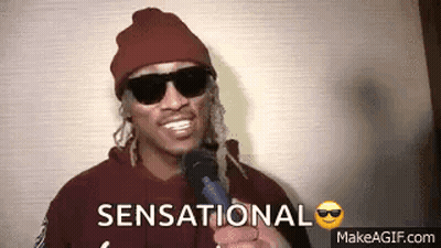 Man In Sunglasses And Beanie Holding Microphone Saying Sensational GIF