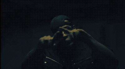 Man In Sunglasses And Beanie Pointing In Dark GIF