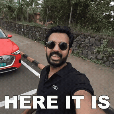 Man In Sunglasses And Black Shirt Says Here It Is In Front Of Red Car GIF