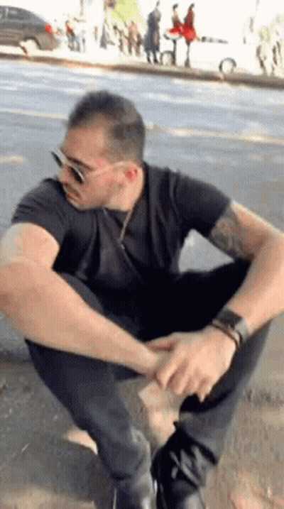 Man In Sunglasses And Black Shirt Squatting GIF