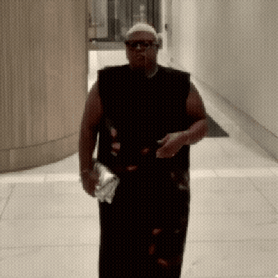 Man in Sunglasses and Black Tank Top Walking Down Hallway