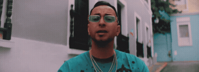 Man In Sunglasses And Blue Shirt In Front Of Buildings GIF