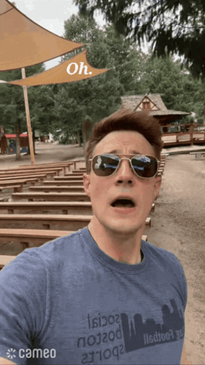 Man In Sunglasses And Cameo Shirt In Front Of Wooden Benches GIF