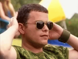 Man In Sunglasses And Camo Shirt Hands On Head GIF