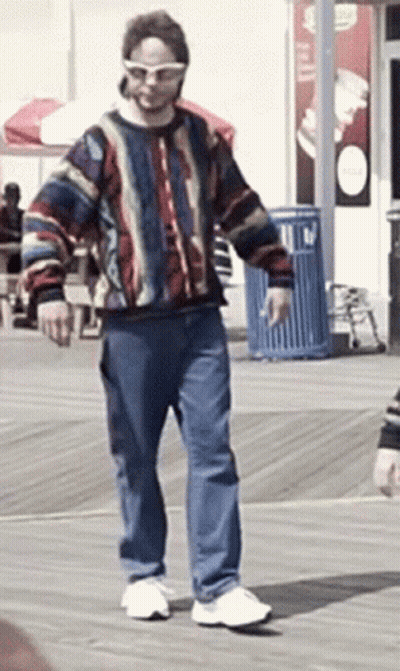 Man In Sunglasses And Colorful Sweater Walking GIF