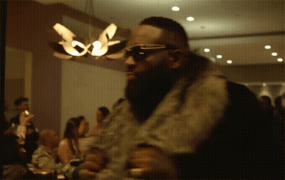 Man In Sunglasses And Fur Coat Before Crowd GIF