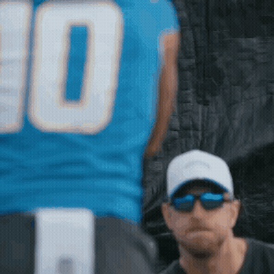 Man In Sunglasses And Hat Beside Football Player In Blue Jersey GIF