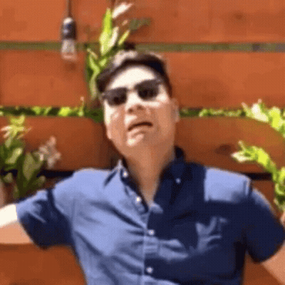 Man In Sunglasses And Hat Making Funny Face In Front Of Wooden Wall GIF