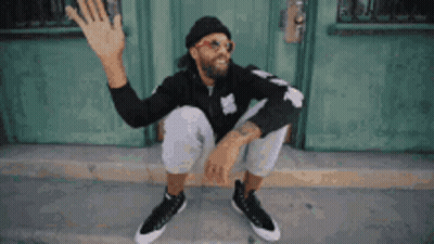 Man In Sunglasses And Hat Sitting Outside Green Door GIF