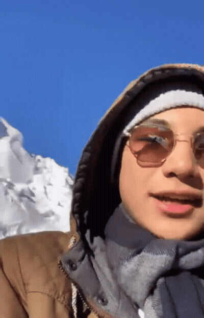 Man In Sunglasses And Hooded Jacket In Front Of Snowy Mountain GIF