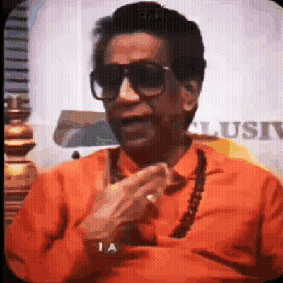 Man In Sunglasses And Orange Shirt Talking On Phone GIF