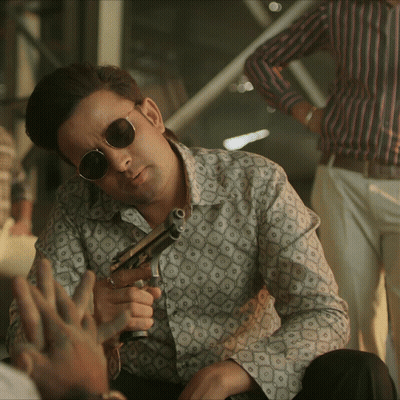 Man In Sunglasses And Patterned Shirt Holding Gun GIF