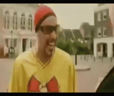 Man In Sunglasses And Red Hat Standing In Front Of Building GIF