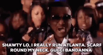 Man In Sunglasses And Scarf Standing In Front Of Group GIF