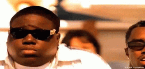 Man In Sunglasses And White Shirt Next To Another Man On Plane GIF