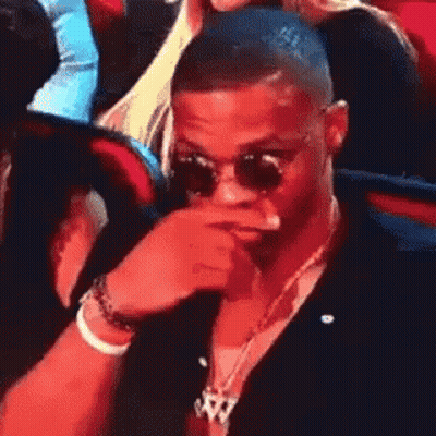 Man In Sunglasses Covering Mouth In Crowd GIF