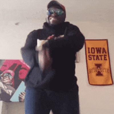 Man In Sunglasses Holding Football In Front Of Iowa State Sign GIF