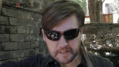 Man In Sunglasses In Front Of Brick Wall With Roundabout Crew GIF