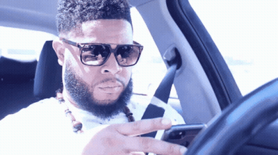 Man In Sunglasses Looking At Phone While Driving GIF