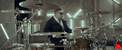 Man In Sunglasses Playing Drums In Front Of Drums Sign GIF
