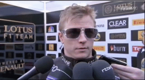 Man In Sunglasses Talking Into Microphone At Lotus F1 Sign GIF