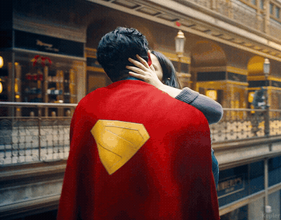 Man In Superman Cape Hugged By Woman GIF