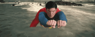 Man In Superman Costume Flying Over Water GIF