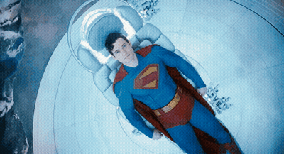 Man In Superman Costume Laying On Bed GIF