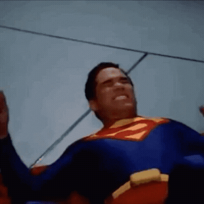 Man In Superman Costume Laying On Ground With Hands Up GIF