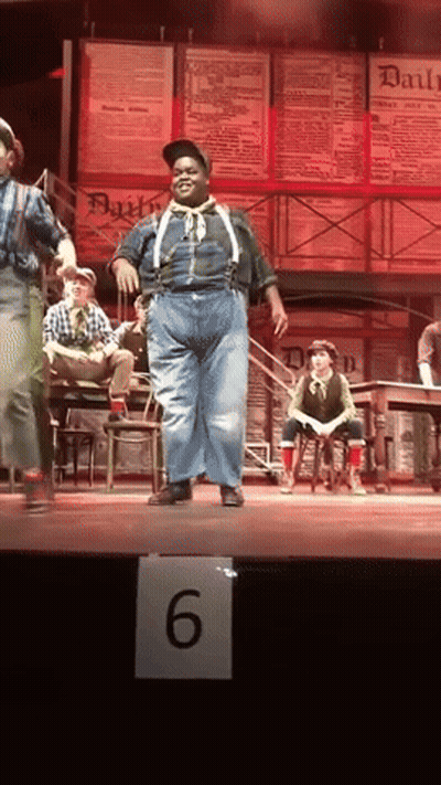 Man In Suspenders Dancing On Stage With Number 6 Sign GIF