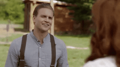 Man In Suspenders Talking To Woman In Park GIF