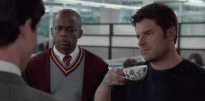 Man In Sweater And Tie Holding Coffee GIF