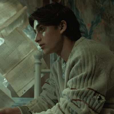 Man In Sweater In Front Of Paper Stack GIF