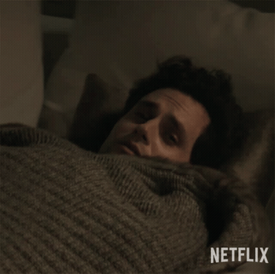 Man In Sweater Laying In Bed With Netflix Logo GIF