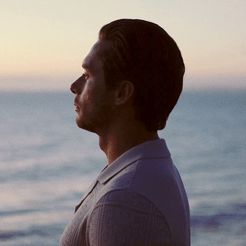 Man In Sweater Looking Out Over Ocean GIF