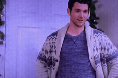 Man In Sweater Smiling By Christmas Tree GIF