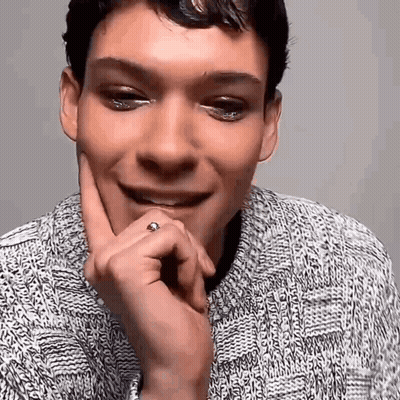 Man In Sweater Smiling With Hand On Chin GIF