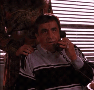 Man In Sweater Talking On Telephone GIF