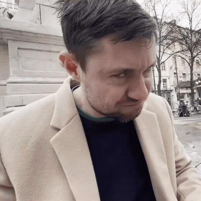 Man In Tan Coat And Black Sweater Making A Face GIF