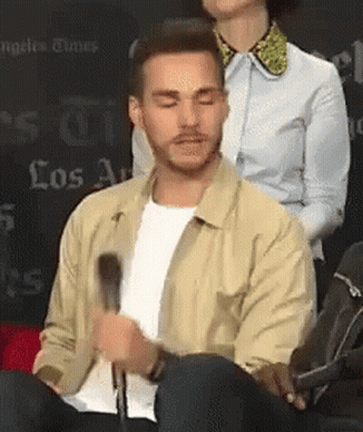 Man In Tan Jacket Sitting At Microphone GIF
