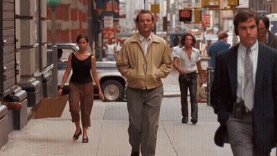 Man In Tan Jacket Walking Down Sidewalk GIF