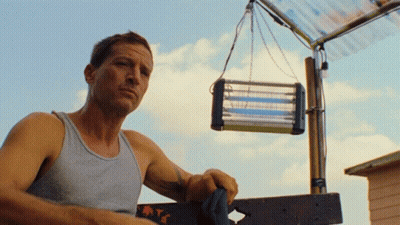 Man In Tank Top Standing Next To Mosquito Killer GIF