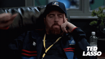 Man In Ted Lasso Jacket Sitting On Couch GIF