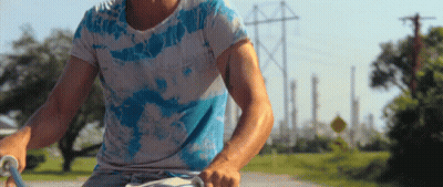 Man In Tie Dye Shirt Riding Bike GIF