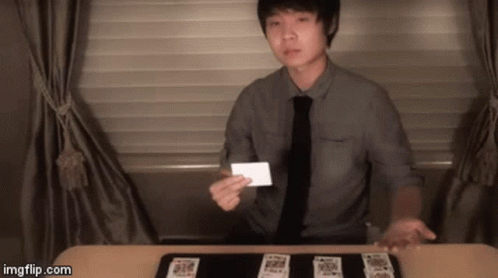 Man In Tie Holding Card In Front Of Table Of Cards GIF