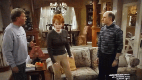 Man In Titans Shirt Talks To Woman And Man In Living Room GIF