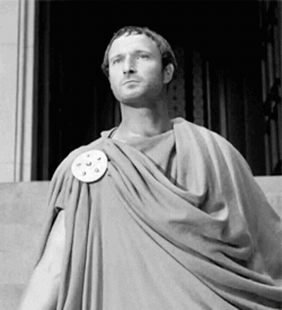 Man In Toga Standing In Front Of Building GIF